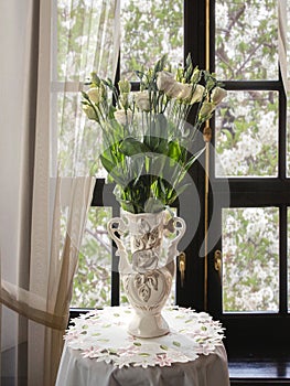 Still life with bouquet of white flowers near the window