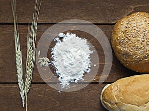 Still life of bread , flour, ears of corn on old wooden table