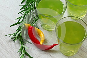 Still life with bright green cocktails on wooden background, chilli pepper and rosemary near