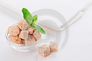 Still life with brown lump cane sugar, on white linen