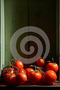 Still Life with a bunch of natural grown Tomatoes. Rustic wood background, antique wooden table