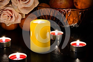 Still life of candles of different colors, flowers and fruits
