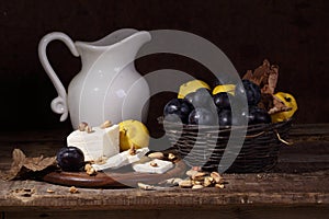 Still life with cheese, quince , plums and white pitcher