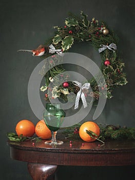 Still life with Christmas wreaths, green glass and oranges