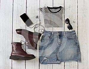 Still life of clothes, denim mini skirt, striped shirt, hat, smartphone and headphones