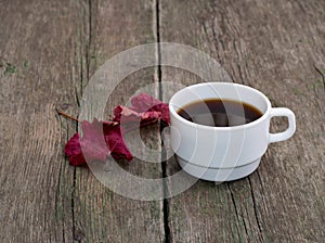 Still life, coffee and brightly red leaf on a wooden table, fall