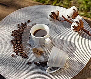 Still life with coffee cup, beans, brown sugar and cotton flower in the sun