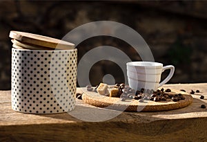 Still life with coffee cup, beans and sugar bowl in the sun