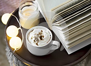 Still life of coffee cup with a book and candle, interior winter weekend concept