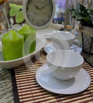 Still life - coffee mugs arranged on a table with vintage clocks and decorative green candles