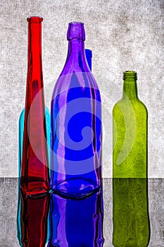 Still life with colored bottles on a reflective surface