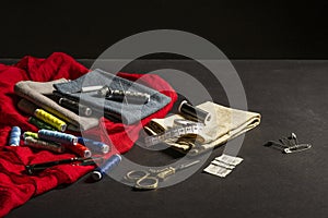 Still life with colored cloths, spools of sewing thread, needles, tape measure, scissors and other accessories