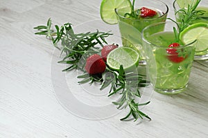 Still life with colorful bright cocktails on wooden background, decorated with rosemary, strawberry and lime