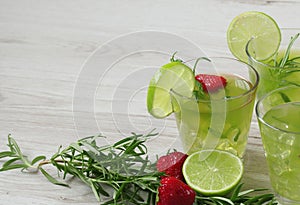 Still life with colorful bright cocktails on wooden background, decorated with rosemary, strawberry and lime