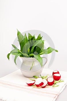 Still life composition with bear's garlic (Allium Ursinum) and sliced radishes