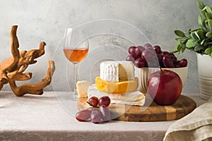 Still life composition with cheese, grapes, nuts and wine glass on table