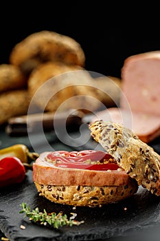 Still life composition of delicious hot dogs and sandwiches with different toppings and dried onion on the dark