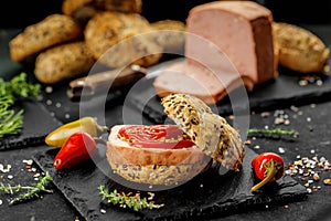 Still life composition of delicious hot dogs and sandwiches with different toppings and dried onion on the dark