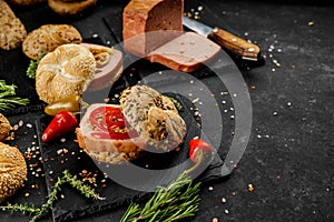 Still life composition of delicious hot dogs and sandwiches with different toppings and dried onion on the dark