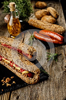 Still life composition of delicious hot dogs and sandwiches with different toppings and dried onion on the dark