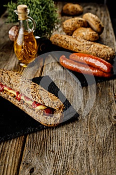 Still life composition of delicious hot dogs and sandwiches with different toppings and dried onion on the dark