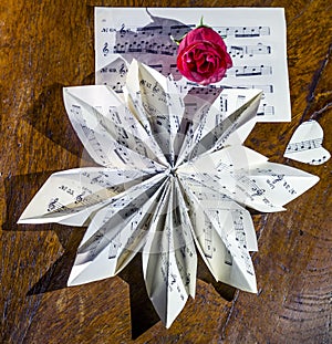 Still life composition made with a musical score folded in the shape of a flower and a red rose