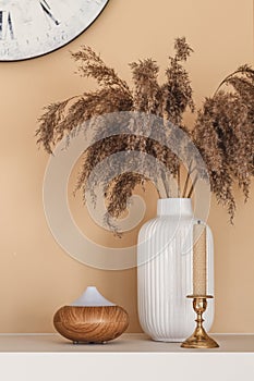 Still life composition with reeds, bee wax candle and essential oil diffuser