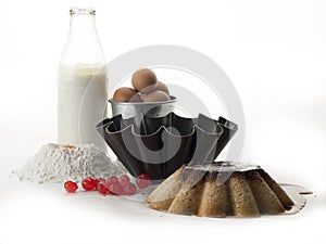 Still life consisting of an egg custard, a curly mold, a bottle of milk, a bowl with eggs, flour and egg yolk