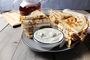 Still life of crepe pancakes with sour cream and tea close-up