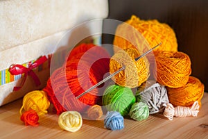 Still life with a crochet hook, various balls of yarn on wooden table with hobby box and dark wall in background