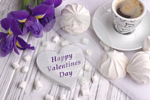 Still life with cup of coffe marshmallow zephyr iris flowers heart sign on white wooden background. Wedding. Valentines Day.