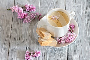 Still life with cup of coffee and spring lilac flower