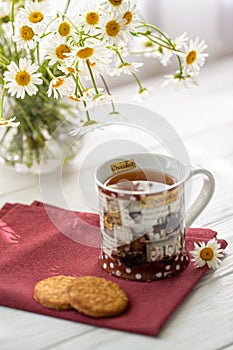 Still life with a cup of tea, cookies and daisies