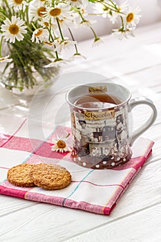 Still life with a cup of tea, cookies and daisies