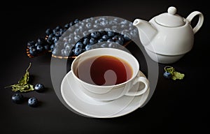 Still life, cup with tea, teapot, blueberry and dry leaves of mellisa