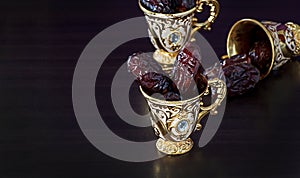 Still life with dates and golden Traditional Arabic coffee set with mini cup. Dark background.