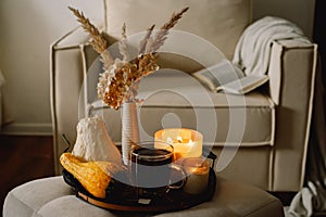 Still life details in home interior of living room. Pumpkin and cup of tea with candles on a serving tray. Rest and Reading