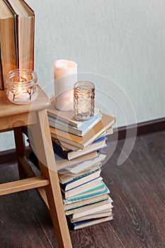 Still life details, stack of old books, candles on rustic bench, concept of seasonal relax time, cozy home lifestyle, autumn