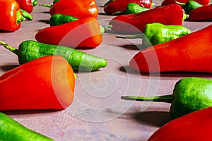 A still life with a dirty pink surface with many crisscrossed green and red peppers