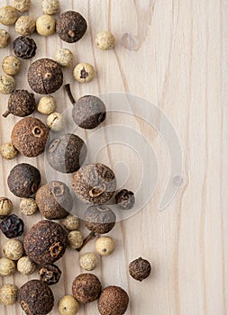 Still life with dried peppercorns on a light wooden background.