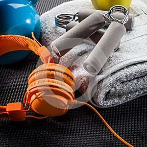 Still-life of earphones, hand grip, towel and kettle bell