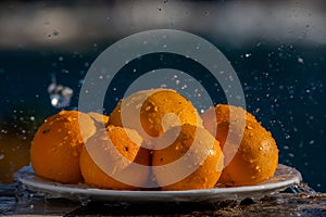 Still life eight oranges on white plate with water drops spraying, selective focus on the front row