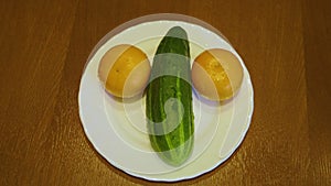 Still life with emoticon made from cucumber and two tangerines on plate