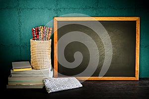 Still life of empty blackboard and colorful pencils with books o