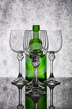 Still life with empty glass goblets and green bottle