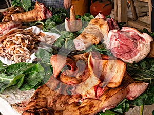 Still life of the exploded view of a pig with a large pig mask and leftover meat on cabbage leaves