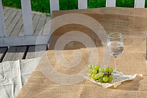 Still life and food photo. A bunch of grapes, a glass of water stand on burlap on a wooden floor