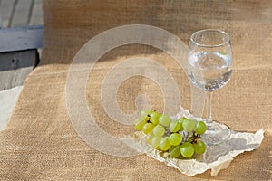 Still life and food photo. A bunch of grapes, a glass of water stand on burlap on a wooden floor