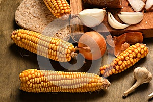 Still life of food in a rural style on a dark wood background, corn and garlic, concept of fresh vegetables and healthy food