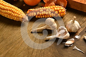 Still life of food in a rural style on a dark wood background, corn and garlic, concept of fresh vegetables and healthy food